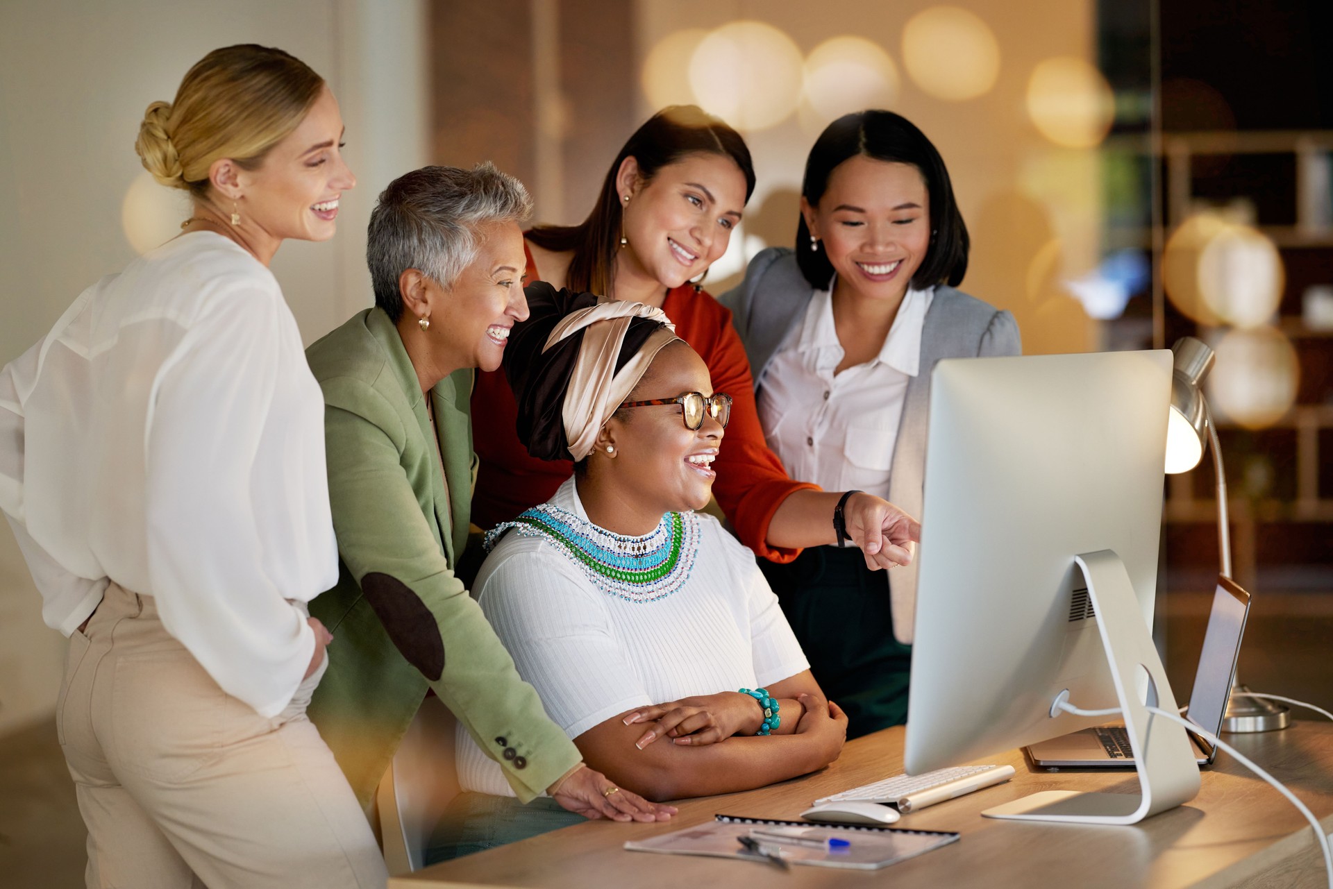 Computer, meeting and a business woman with her team, working online in the office at night for development. Teamwork, diversity and coaching with a senior female manager training her staff at work